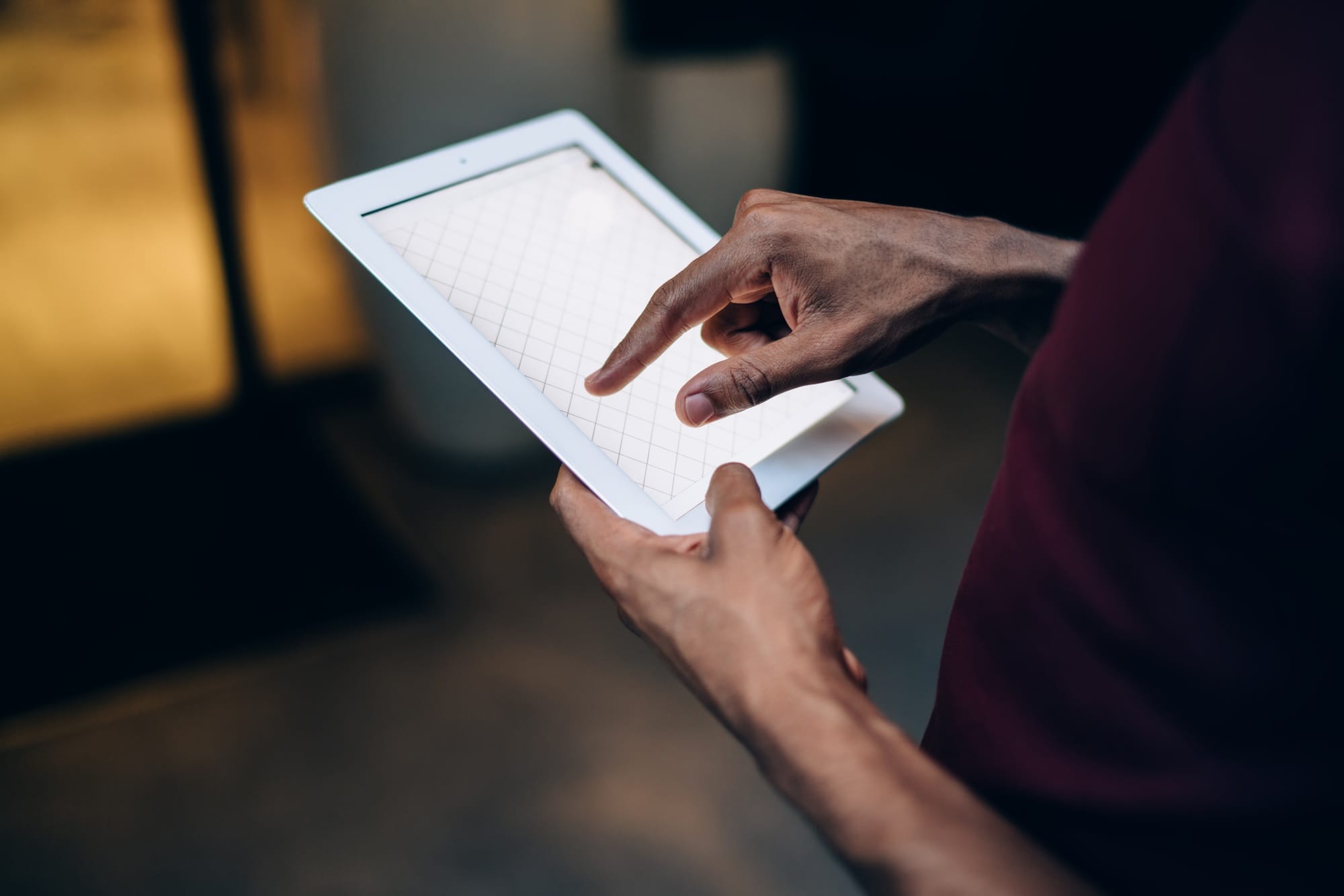 selective focus on touchscreen of modern digital tablet in hands of male blogger with dark skin